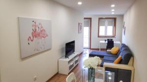 Una sala de estar con un sofá azul y un televisor. en Porta 116 - Free Private Parking, en Vila Real