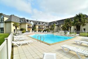 ein Pool mit weißen Stühlen und ein Resort in der Unterkunft Kermael - Appt vue mer et piscine partagée in Saint-Briac-sur-Mer
