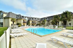 una piscina con sillas blancas y un complejo en Kermael - Appt vue mer et piscine partagée, en Saint-Briac-sur-Mer