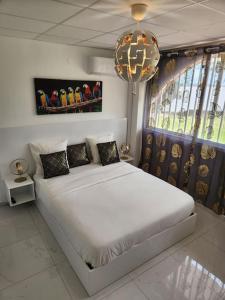 a bedroom with a white bed and a chandelier at Hello-Guyane, Marina 5, Studio Prestige 5 étoiles in Saint-Laurent du Maroni