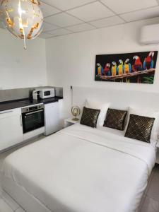 a white bedroom with a white bed and a kitchen at Hello-Guyane, Marina 5, Studio Prestige 5 étoiles in Saint-Laurent du Maroni