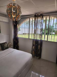 a bedroom with a bed and a chandelier and windows at Hello-Guyane, Marina 5, Studio Prestige 5 étoiles in Saint-Laurent du Maroni