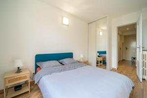 1 dormitorio con 1 cama grande y cabecero azul en Le Rosier - 20 min de Paris et d'Orly, en Vitry-sur-Seine