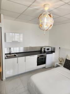 a white kitchen with a bed and a chandelier at Hello-Guyane, Marina 5, Studio Prestige 5 étoiles in Saint-Laurent du Maroni
