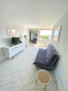 a living room with a couch and a tv at Appartement spacieux 65M2, avec piscine et parking in Fréjus