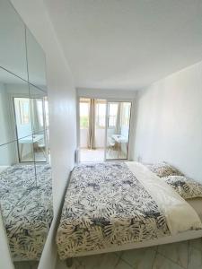 a white bedroom with a bed and a mirror at Appartement spacieux 65M2, avec piscine et parking in Fréjus