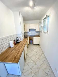 a kitchen with white cabinets and a wooden counter top at Appartement spacieux 65M2, avec piscine et parking in Fréjus