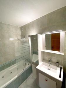 a bathroom with a sink and a tub and a mirror at Appartement spacieux 65M2, avec piscine et parking in Fréjus