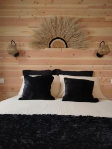 a bed with black pillows in a bedroom with a wooden wall at Chalet, aux portes du Morvan in Voudenay-lʼEglise