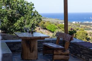 een houten tafel en een stoel op een patio met uitzicht op de oceaan bij Richie's Sea View Romantic Residences in Ándros