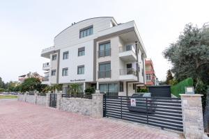 a white building with a fence in front of it at Rose Residence - Trendy Apartments Near The Beach in Antalya