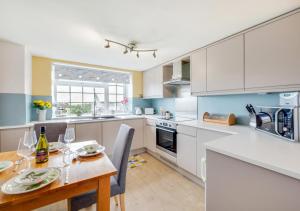 a kitchen with a table and chairs and a kitchen with white cabinets at Angorfa Aberaeron Apartment in Aberaeron