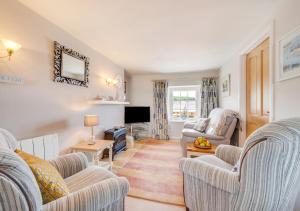 a living room with two chairs and a television at Angorfa Aberaeron Apartment in Aberaeron