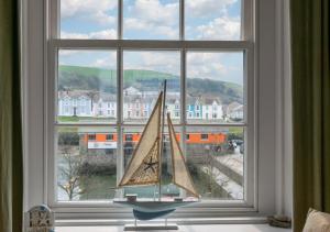 a toy sailboat sitting in a window with a view at Angorfa Aberaeron Apartment in Aberaeron