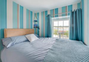 a bedroom with a bed with blue and white stripes at Angorfa Aberaeron Apartment in Aberaeron