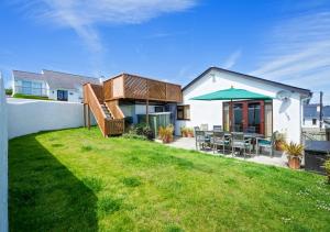 uma casa com um quintal com cadeiras e um guarda-sol em Kookaburra em Abersoch