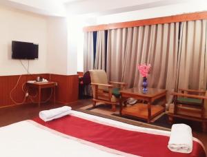 a room with a bed and a table and a tv at Roys Rabdentse Residency in Pelling