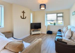 a living room with two couches and a flat screen tv at Maes Gwyn in Llanbedrog