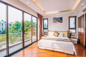a bedroom with a large bed and large windows at Villa FLC Sầm Sơn in Sầm Sơn
