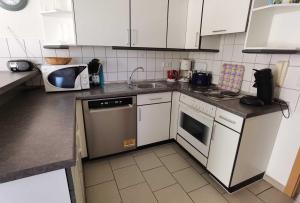 オストゼーバート・カールスハーゲンにあるFewo Sommergarten 4005_OLIVの白いキャビネット、シンク、食器洗い機付きのキッチンが備わります。