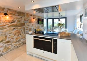 a kitchen with a stone wall and a counter at 1 Fron Dirion in Llanbedrog
