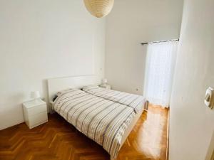 Cama en habitación blanca con suelo de madera en Pet-friendly two-room family apartment in magical Bale, en Bale