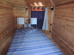 1 cama en una cabaña de madera con ventana en CHALET ATYPIQUE LOLA type KOTA location en gîte, en Chazemais