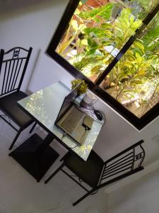 a laptop sitting on a glass table next to a window at Tiny House Loft Style in Digos
