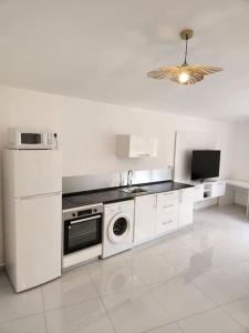 a white kitchen with a refrigerator and a dishwasher at Hello-Guyane, Marina 6, Suite Prestige 5 étoiles in Saint-Laurent du Maroni