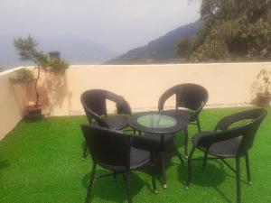 four chairs and a glass table on a lawn at Roys Rabdentse Residency in Pelling