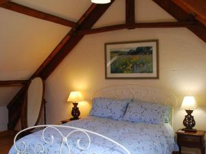 een slaapkamer met een bed met 2 lampen en een schilderij bij Nice cottage in Sainte-Marguerite-d'Elle with garden in Sainte-Marguerite-dʼElle