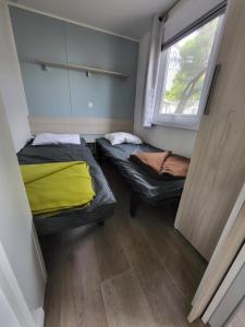 two beds in a small room with a window at Mobil-home (Clim)- Camping Narbonne-Plage 4* - 019 in Narbonne-Plage