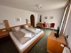 a bedroom with a large bed and a desk with a television at Gasthof Schönblick Rußbach in Gseng