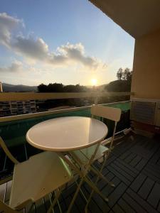 una mesa y sillas en un balcón con vistas a la puesta de sol en Studio avec Clim, Parking et Balcon - 3 personnes, en Bormes-les-Mimosas