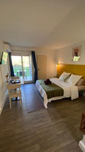ein Schlafzimmer mit einem großen Bett und einem Tisch in der Unterkunft Joli Appartement 27m2 Oasis Provençale en village vacances en Camargue in Arles