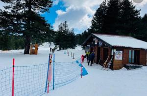 un lodge de esquí con nieve en el suelo y gente parada fuera en Rifugio Mareneve le Villette, en Linguaglossa