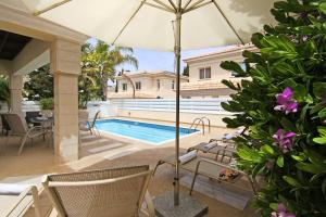 a patio with a swimming pool and an umbrella at Villa Alyson in Paralimni