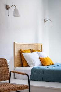un letto con cuscini gialli e bianchi e una sedia di Cath's Loft a Skopelos Town