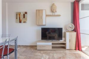 a living room with a flat screen tv and a table at Lightbooking Teror Playa del Ingles in San Bartolomé