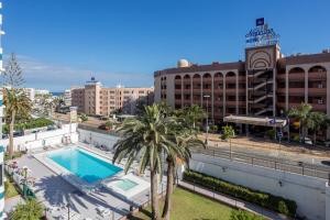 a view of a building with a swimming pool and palm trees at Lightbooking Teror Playa del Ingles in San Bartolomé