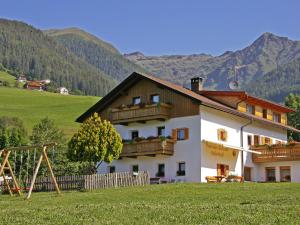 a building with a playground in front of a mountain at Pension Aichner in Terento