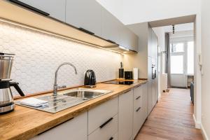 a kitchen with white cabinets and a sink at Neues Design-Apartment in Friedrichshain in Berlin