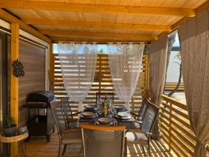 una mesa y sillas en un porche con cortinas en Mobile Home Saky, Camp Soline en Biograd na Moru