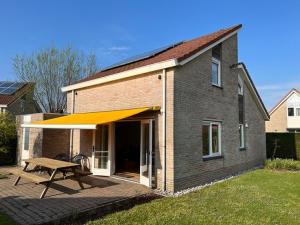 ein Haus mit einer Terrasse mit gelber Markise in der Unterkunft Kustverhuur, Park Scheldeveste, Schelde 76 in Breskens