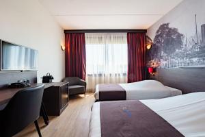 a hotel room with two beds and a desk at Bastion Hotel Barendrecht in Barendrecht
