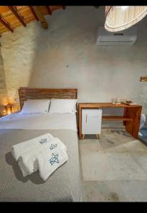 Un dormitorio con una cama y un escritorio con toallas. en Pousada Estrela Peroba, en Icapuí