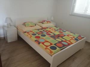 a bed with a colorful comforter on it in a bedroom at Apartman Put 2 in Baška