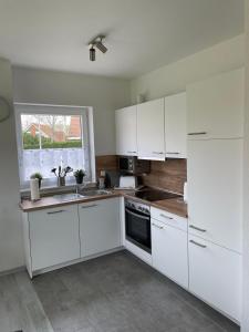 a white kitchen with white cabinets and a sink at Strandläufer in Butjadingen OT Tossens
