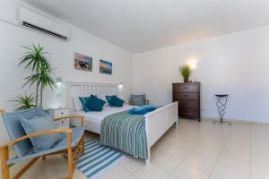 - une chambre avec un lit doté d'oreillers bleus et d'une chaise dans l'établissement Apartment Feliz, à Carvoeiro