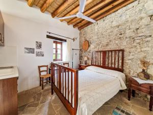 - une chambre avec un lit et un mur en pierre dans l'établissement Sanders Village, à Vasa Kilaniou